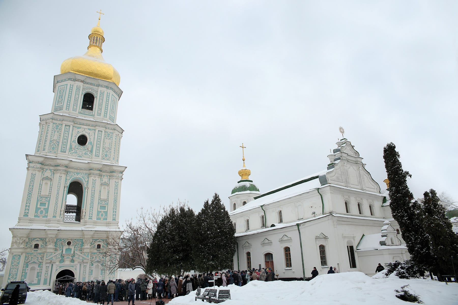 a long line of people stand waiting to enter a cathedral.