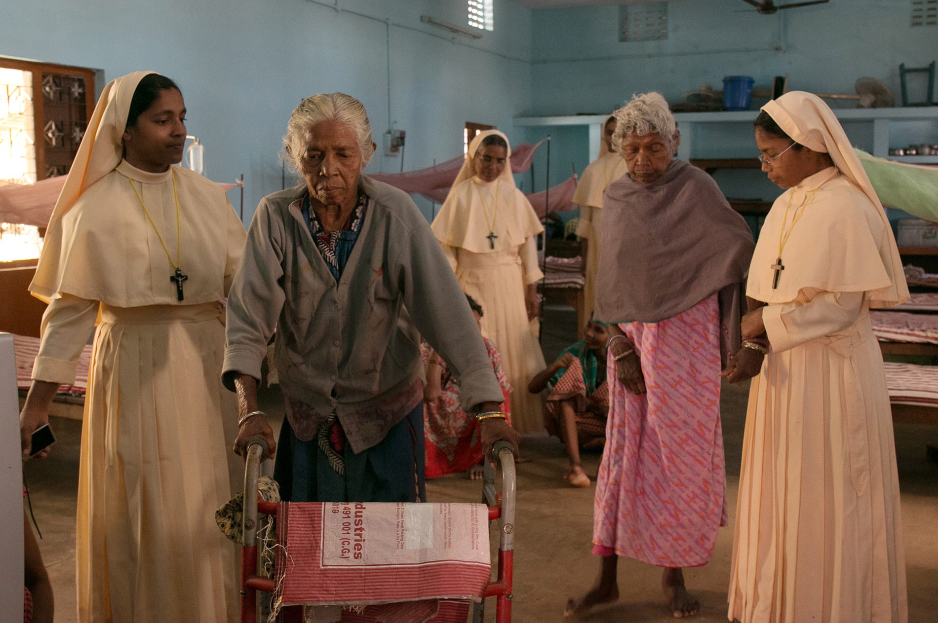 nuns help elderly residents walk.