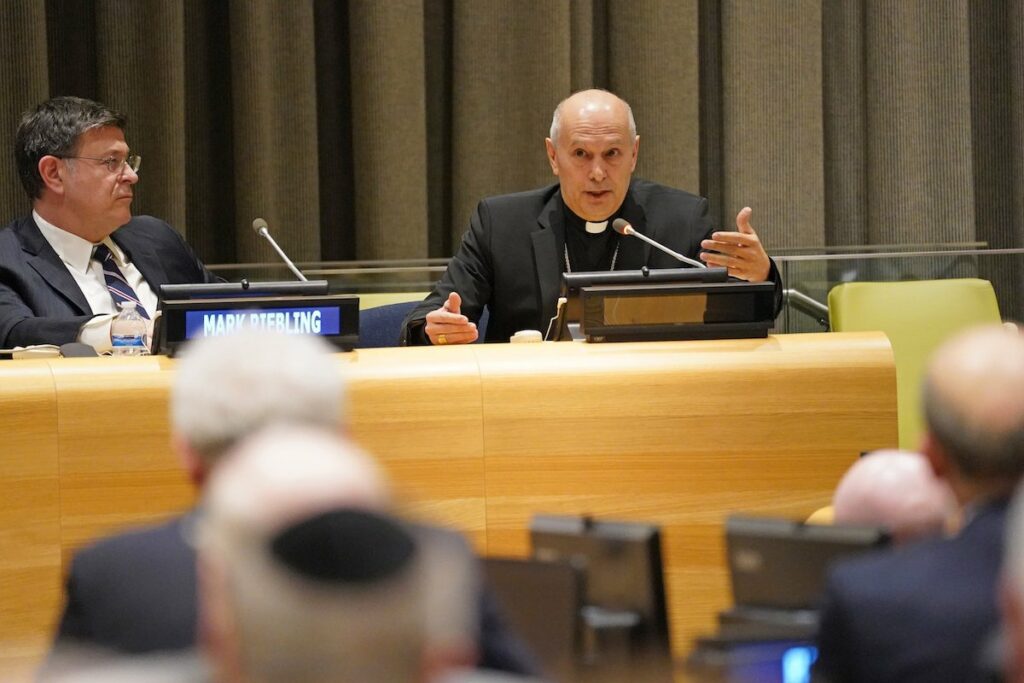 El arzobispo Gabriele Caccia habla por un micrófono mientras está sentado en la ONU.
