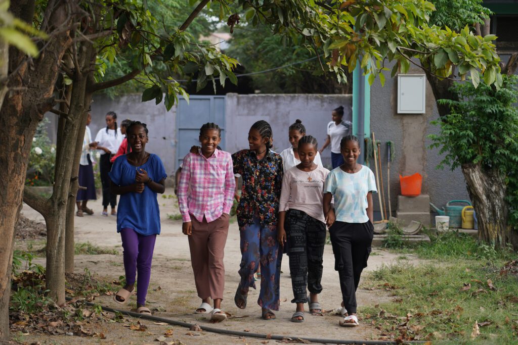 Grupo de niñas sonrientes camina en patio de hogar para niñas en Etiopía.