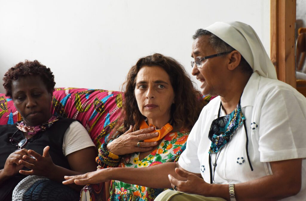 Una refugiada africana, una doctora y una misionera comboniana conversan en un centro en Tel Aviv.