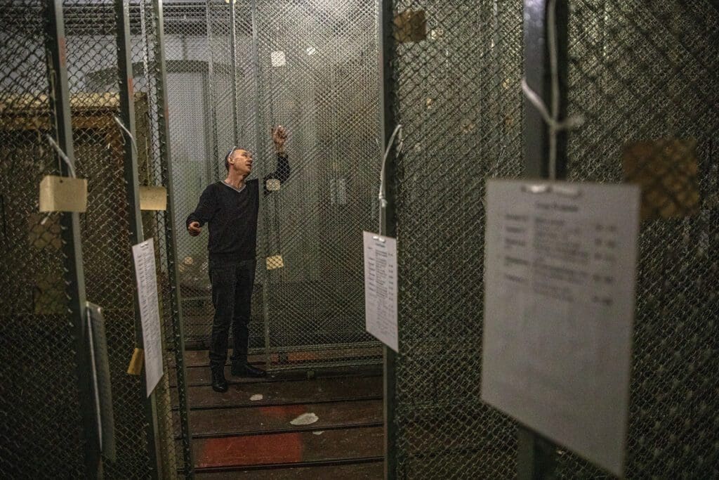 Hombre parado entre estantes vacíos de un museo.