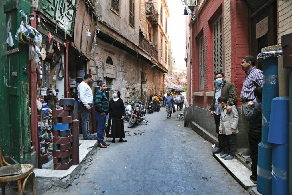 Hermana religiosa en una calle de un vecindario de Egipto. Otras personas caminan.