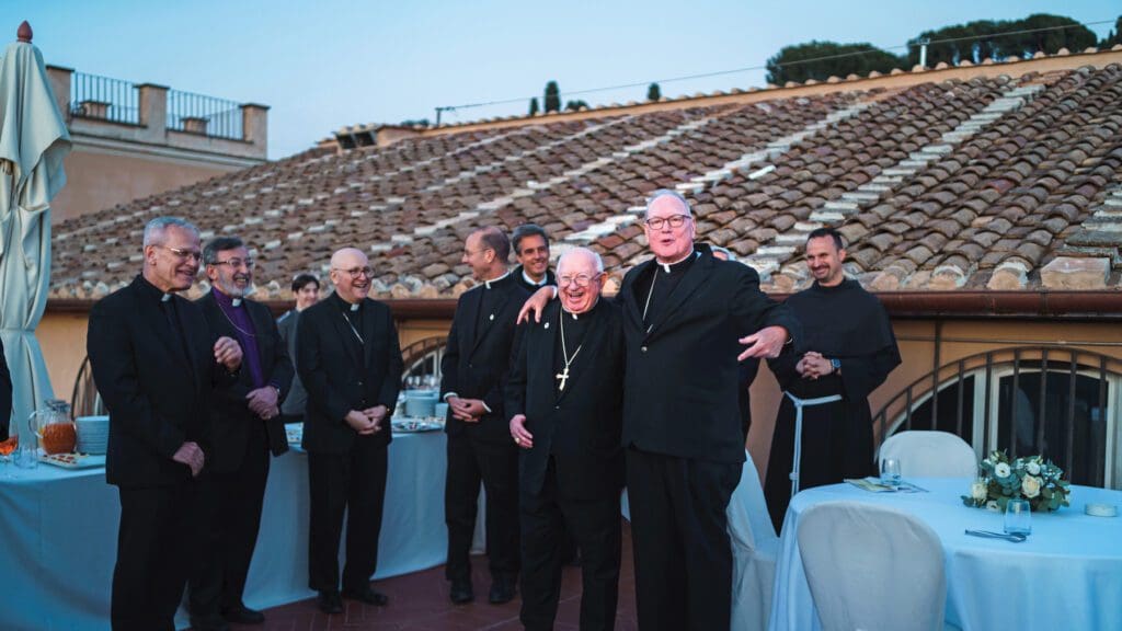 Grupo de sacerdotes sonriendo al lado de un tejado.