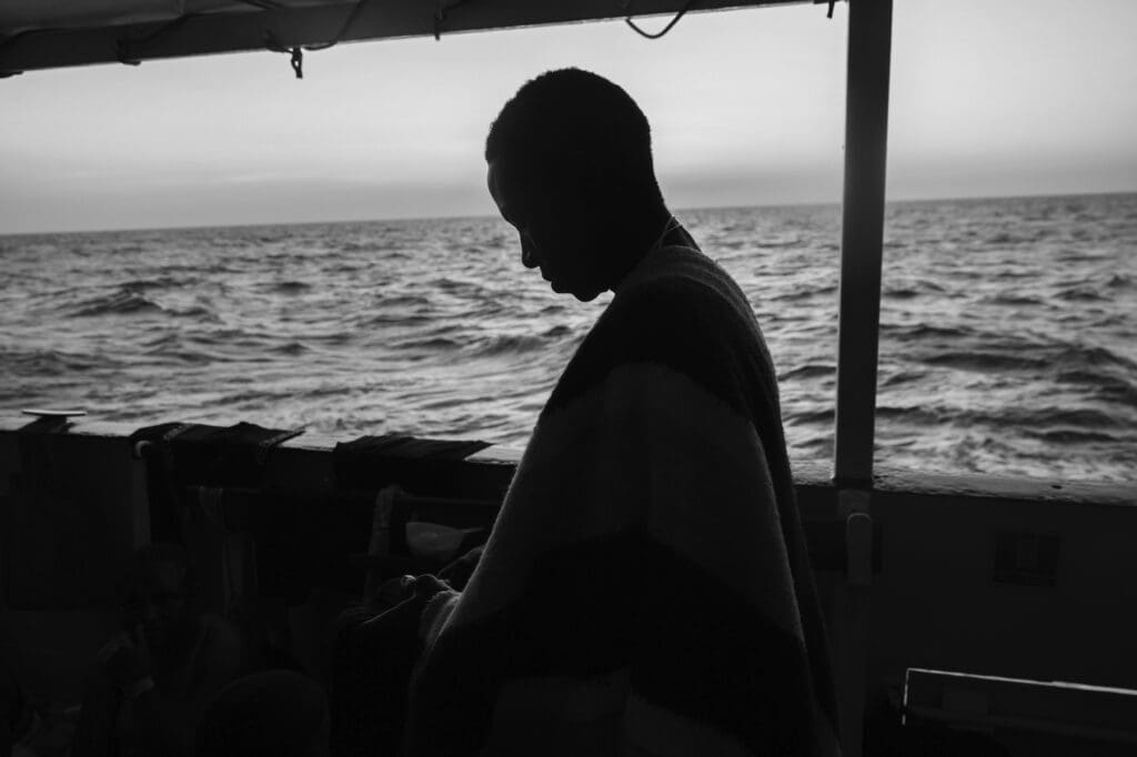 Sombra de un migrante a bordo de un barco que rescató a 194 migrantes en el mar.
