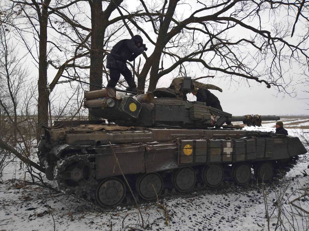 Hombre toma foto parado sobre tanque de guerra.