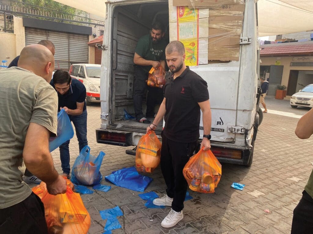 Hombre vestido de negro en frente de una camioneta carga bolsas de ayuda.