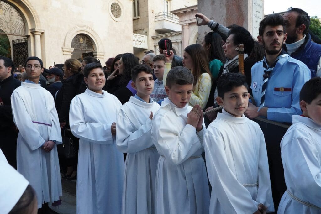 Monaguillos vestidos de blanco participan en procesión.