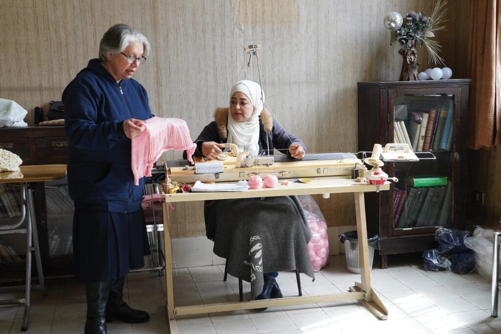 Una mujer revisa una prenda hecha por costurera sentada en máquina de coser.