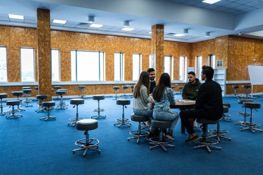 Cinco jóvenes sentados en una mesa redonda en una sala de universidad en Erbil.