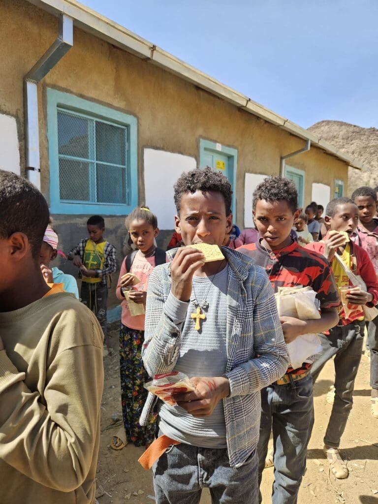 Grupo de adolescentes en una calle de Etiopía comiendo galletas nutricionales.