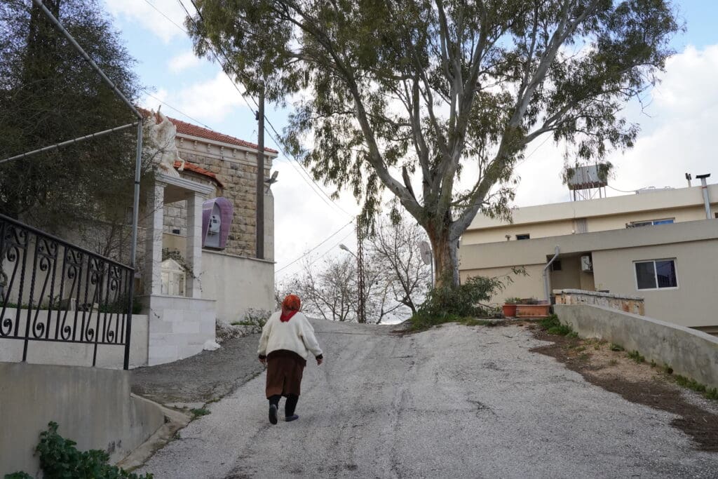 Una mujer, vista de espalda, sube un camino empinado al lado de una iglesia en Líbano.