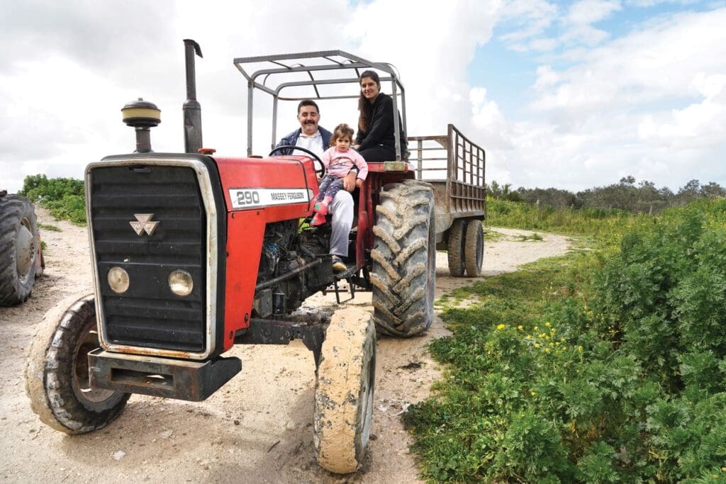 Un uomo, sua moglie e suo figlio siedono in un trattore agricolo.