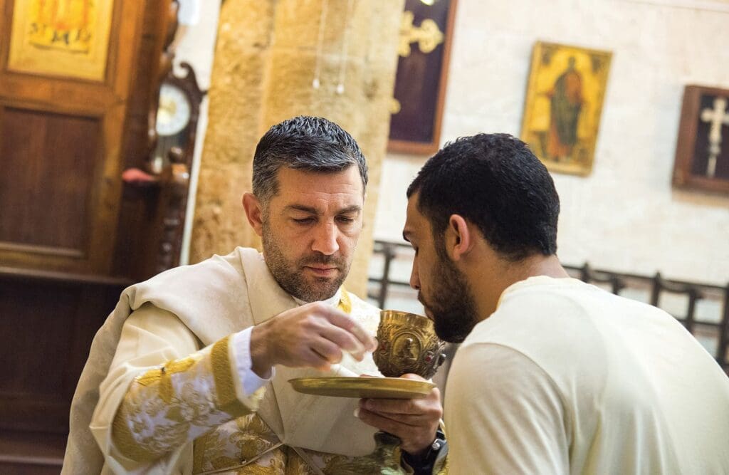 Un sacerdote dà la comunione in una chiesa in Israele.