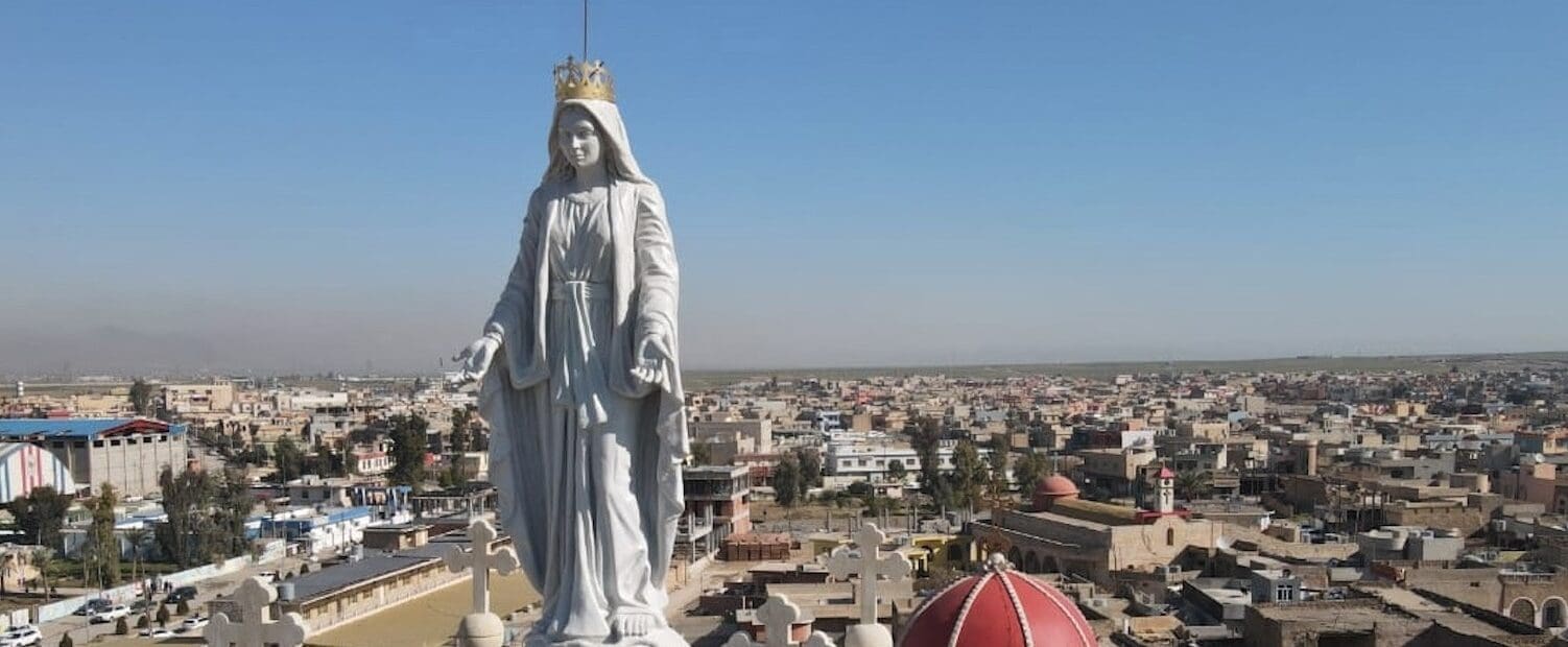 Primo piano di una statua di Maria e vista dall'alto della città di Qaraqosh, in Iraq.