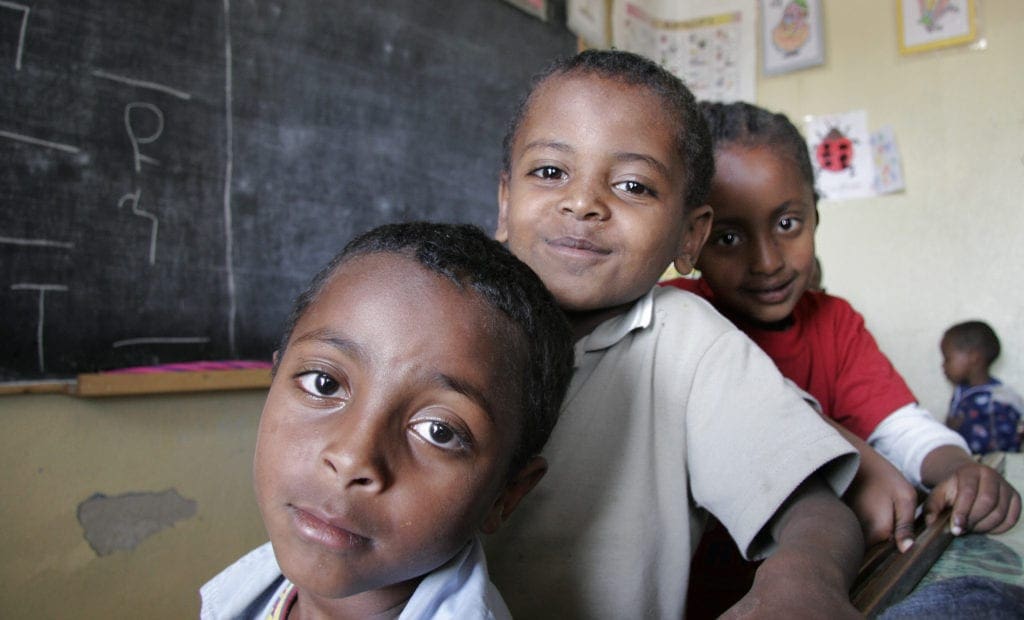 young students stand in a classroom.