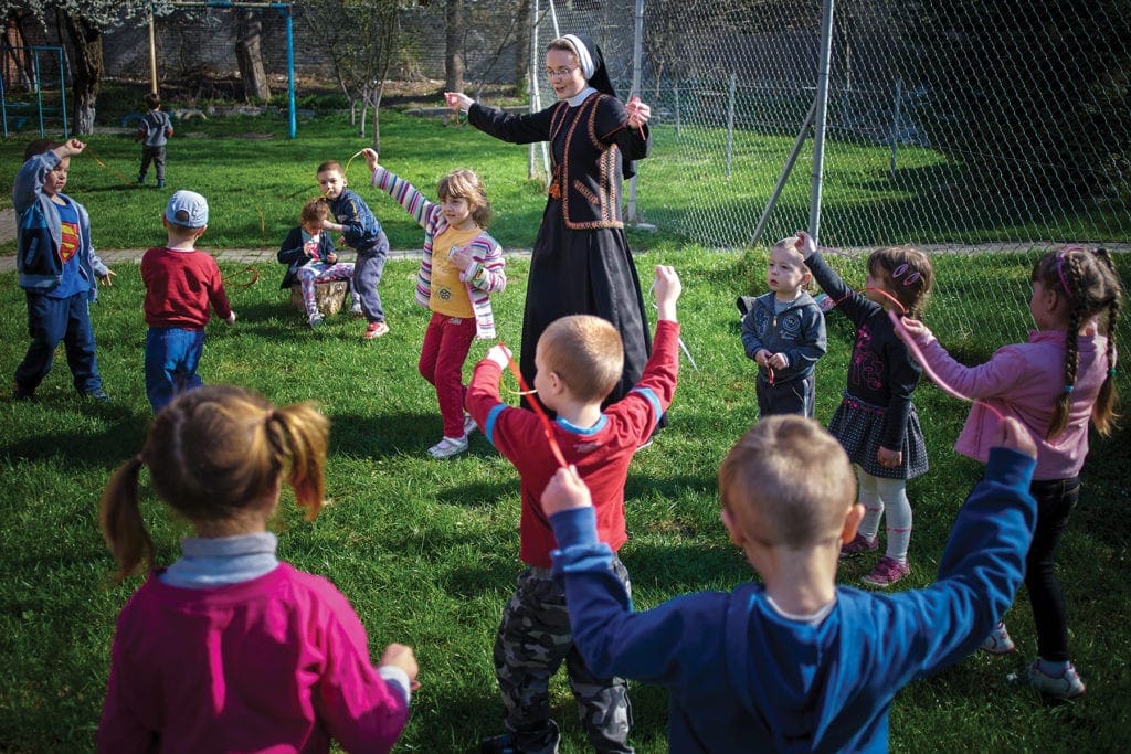 A nun plays outside with a crowd of children in the eastern european nation of ukraine.