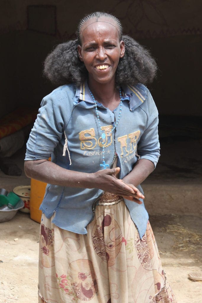A woman smiles as she stands in the sunlight.