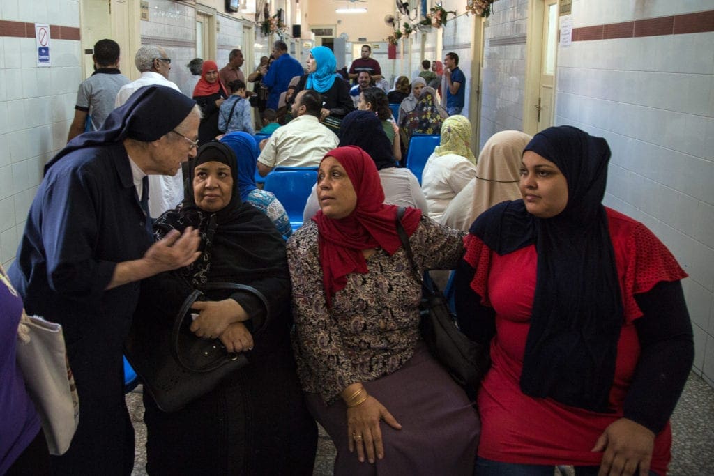 Sister Simone speaks to three women seated in a waiting area.