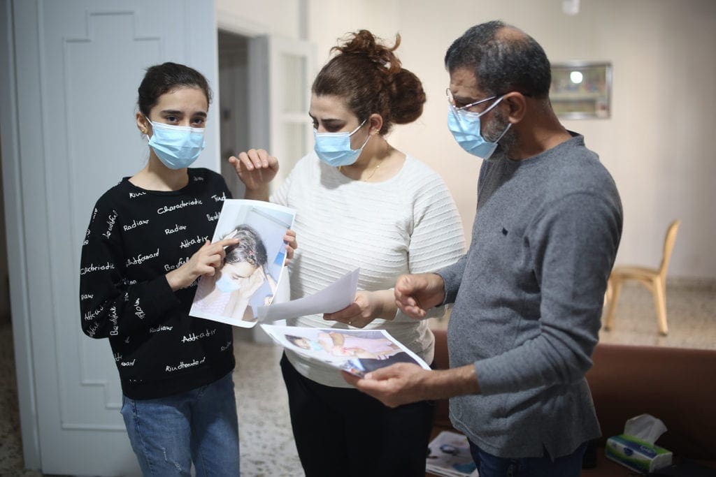 a young woman stands beside her parents holding a photo.