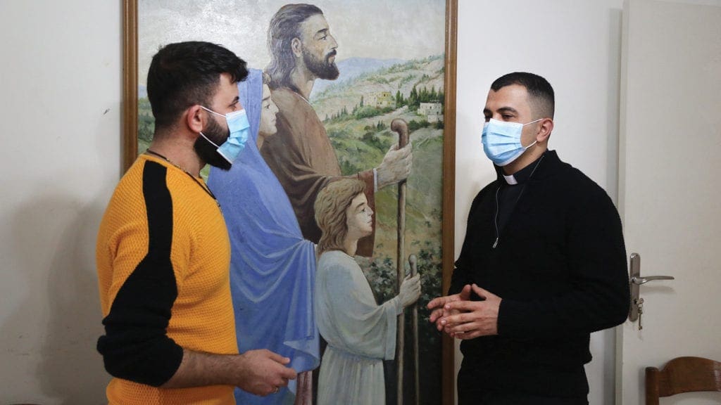a priest chats with a young man.
