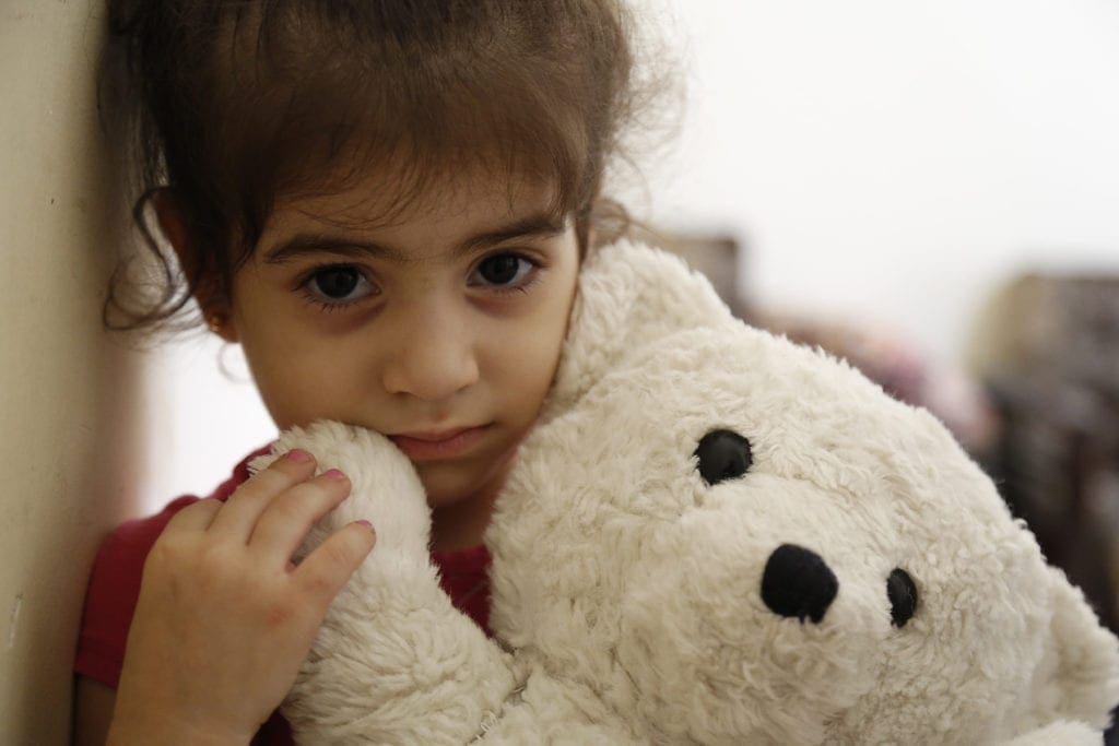 a young girl holds a teddy bear.