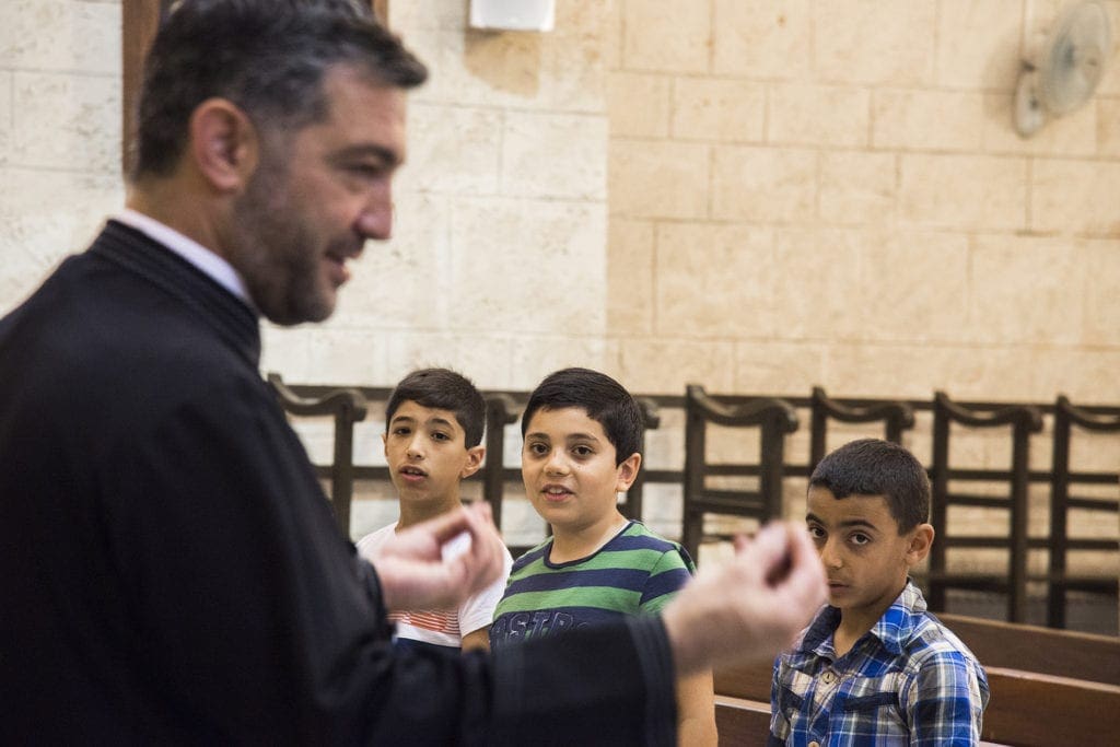 priest talks to children in a church in the middle east.