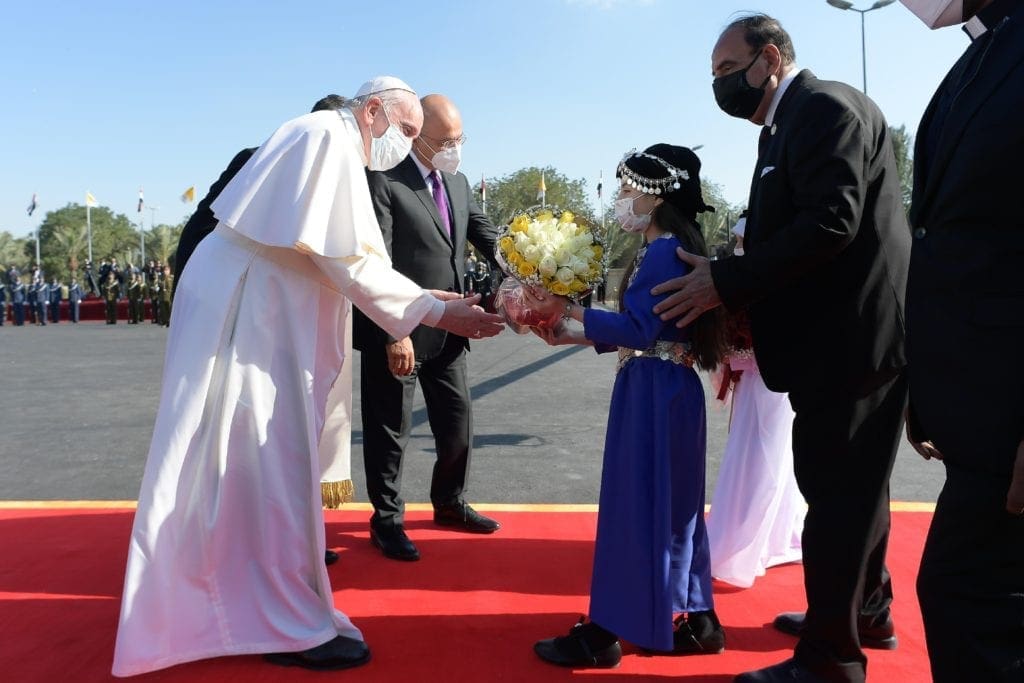 Pope Francis receives flowers from children during a welcoming ceremony with Iraqi President Barham Salih at the presidential palace in Baghdad on 5 March