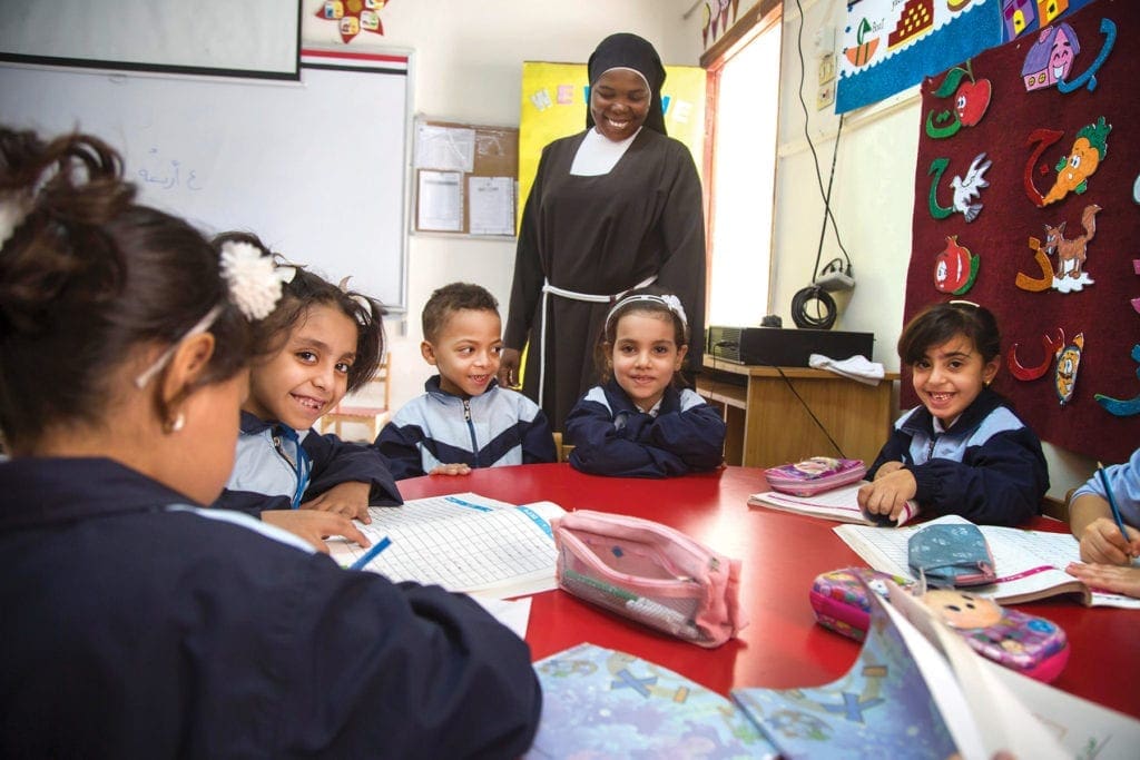 a nun watches over children studying.