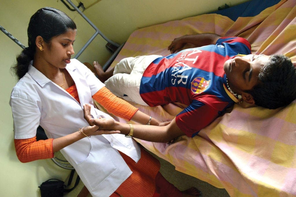 a physical therapist assists a young man.