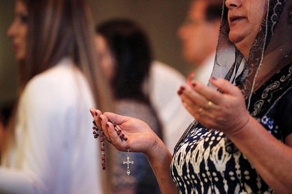 a woman holds a rosary as she prays.