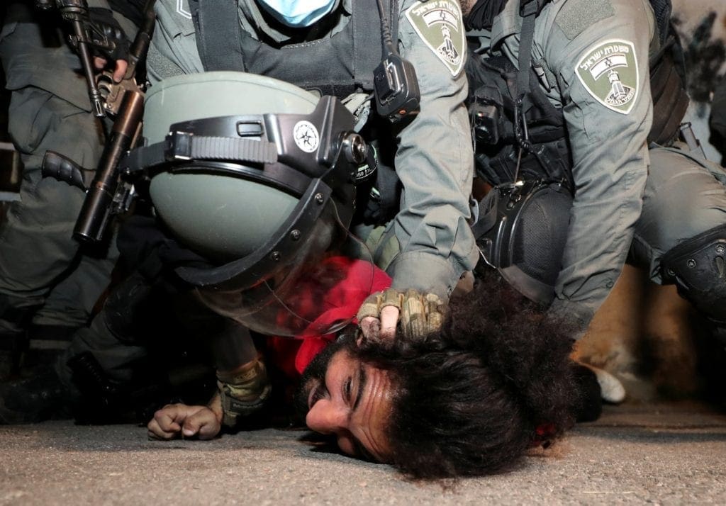 A Palestinian protester is pinned to the ground by Israeli border police.