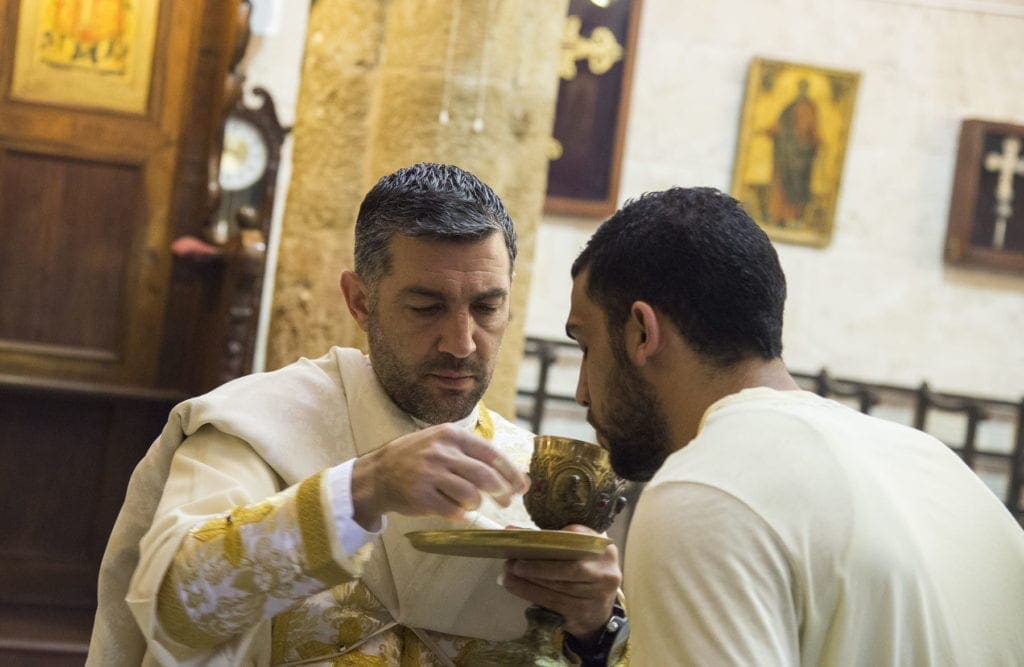a priest gives communion in a church in Israel.