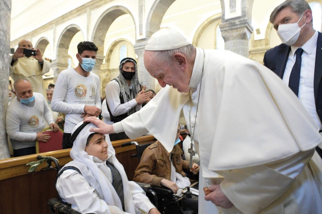 the pope blesses a child seated in church.