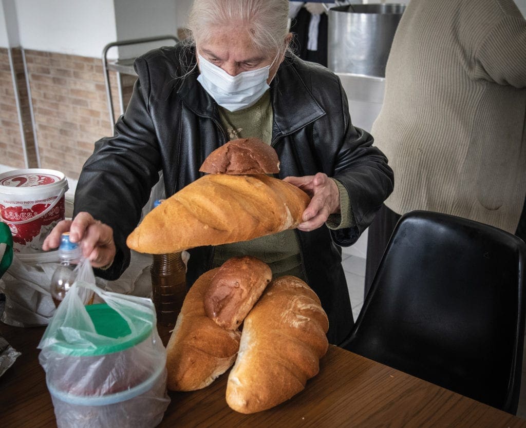 a woman packs up some bread to take home from a soup kitchen.