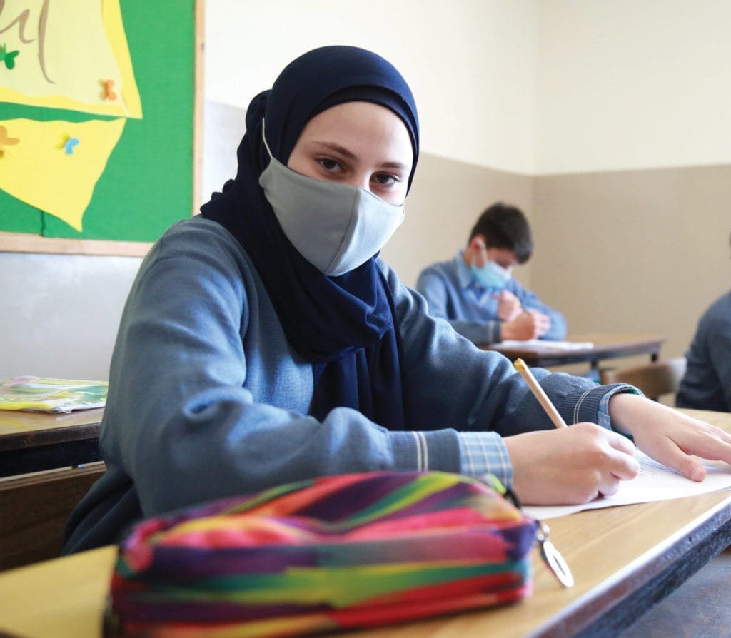 a masked student attends class in Lebanon.