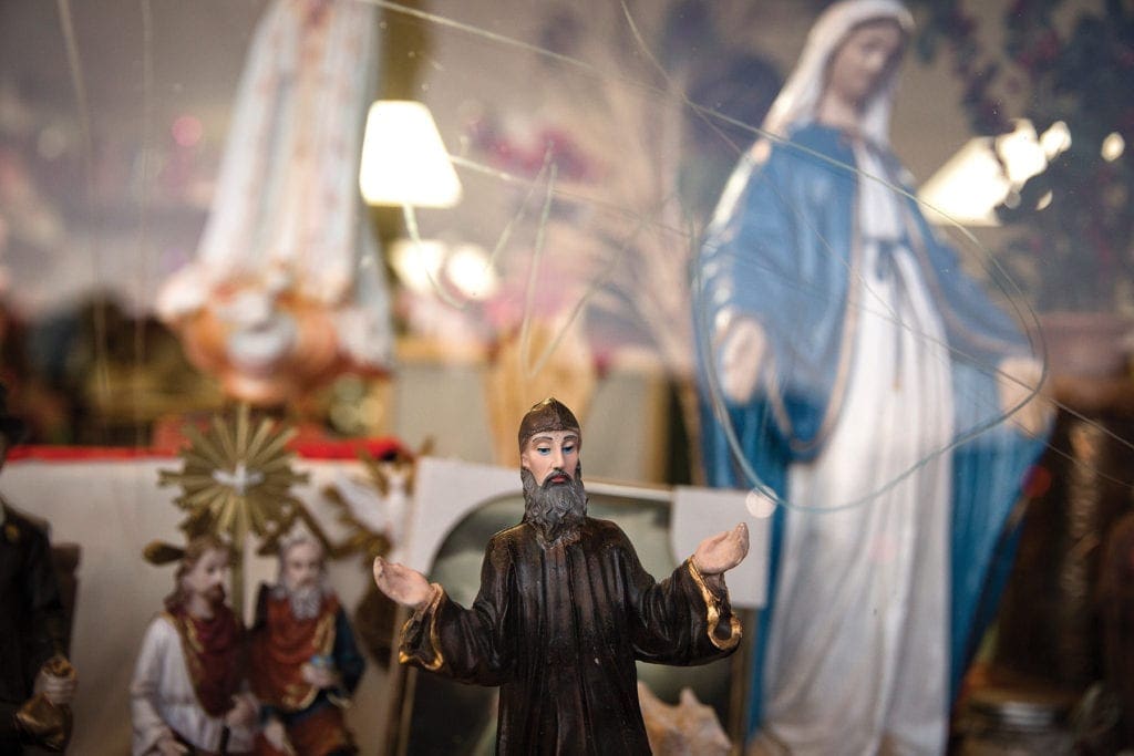 Christian statuary is seen through a storefront window.
