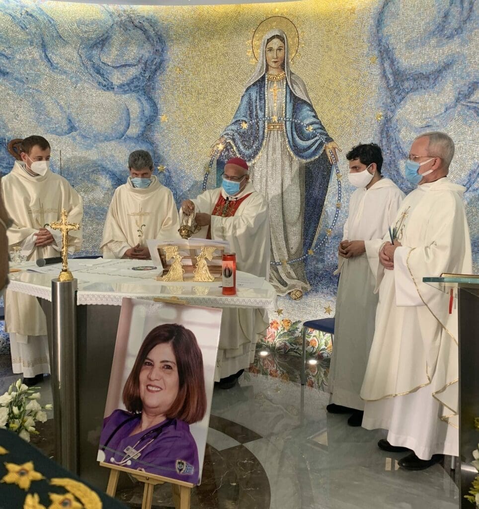 CNEWA president Monsignor Peter Vaccari, far right, is among the concelebrants of a Mass at the Rosary Sisters Chapel at Geitaoui Hospital in Beirut. Bishop Cesar Essayan, the Latin-rite bishop of Beirut, presides as the main celebrant. The woman in the portrait is Jacqueline, a 60-year-old hospital nurse who died as a result of the explosion.