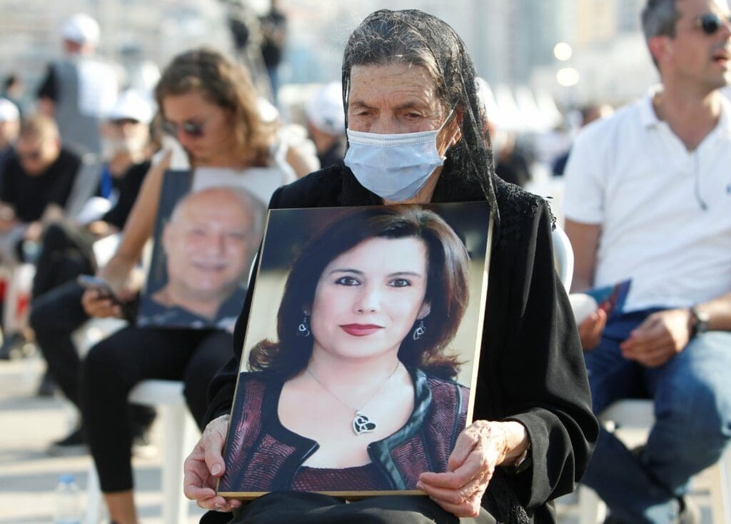 A relative holds a portrait of a victim during a Mass to mark the one-year anniversary of Beirut's port blast on 4 August.