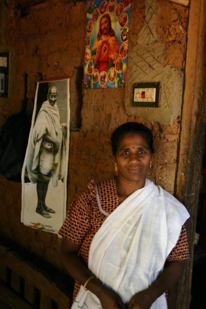 A Christian woman at Bhorathannoor Ambeaker Harigen Colony poses in her home, where images of the Sacred Heart of Jesus and Mahatma Gandhi grace her wall.