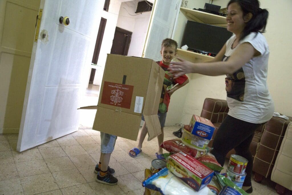 Mrs. Chahine and her two sons play with an empty box that had contained food relief supplies.
