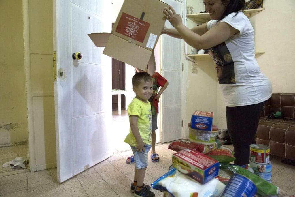 Mrs. Chahine and her two sons play with an empty box that had contained food relief supplies.