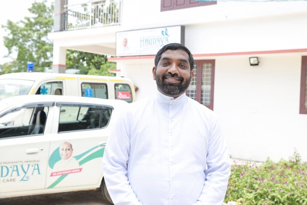 portrait of father thomas kannampilly, standing outside of the center he directs in southern india.