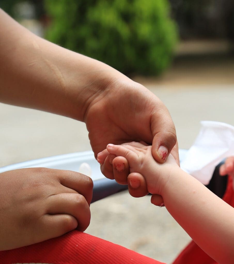 closeup of an adult hand holding a toddler's hand at maryam and martha.