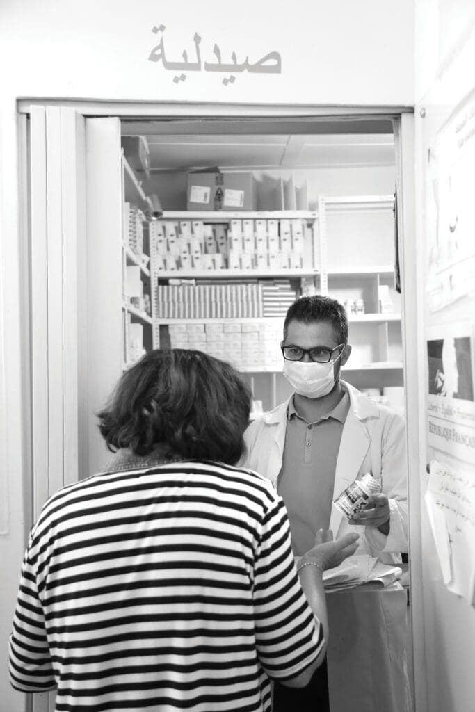 health care worker at pharmacy window distributing medicine.