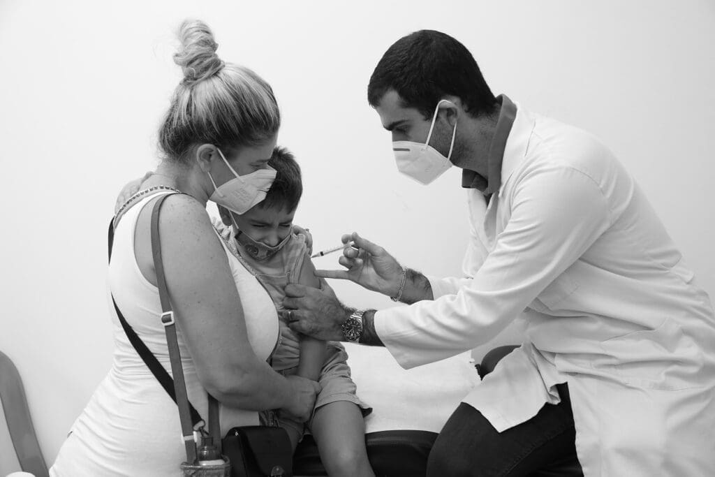 a child winces as a doctor administers a needle.