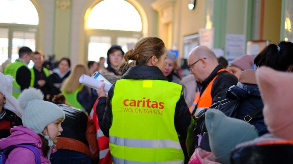 A Caritas volunteer among newly arrived Ukrainian refugees at Przemysl train station in Poland.