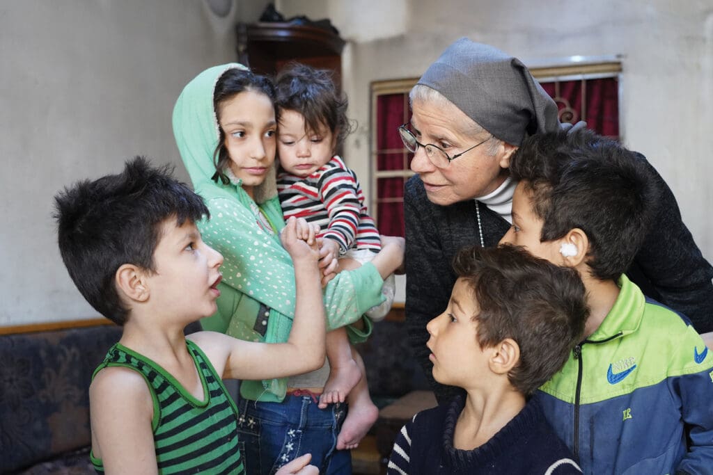 Sister Joseph-Marie Shanaa of the Sisters of Charity of Besançon speaks with children in Damascus, whose family receives food, milk and rent assistance through a CNEWA-sponsored program