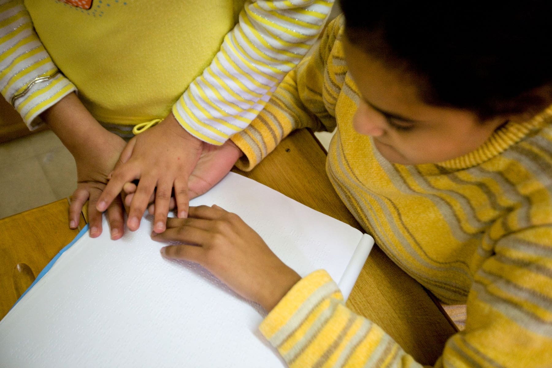 two children clasp hands while they study in a home in Alexandria, Egypt.