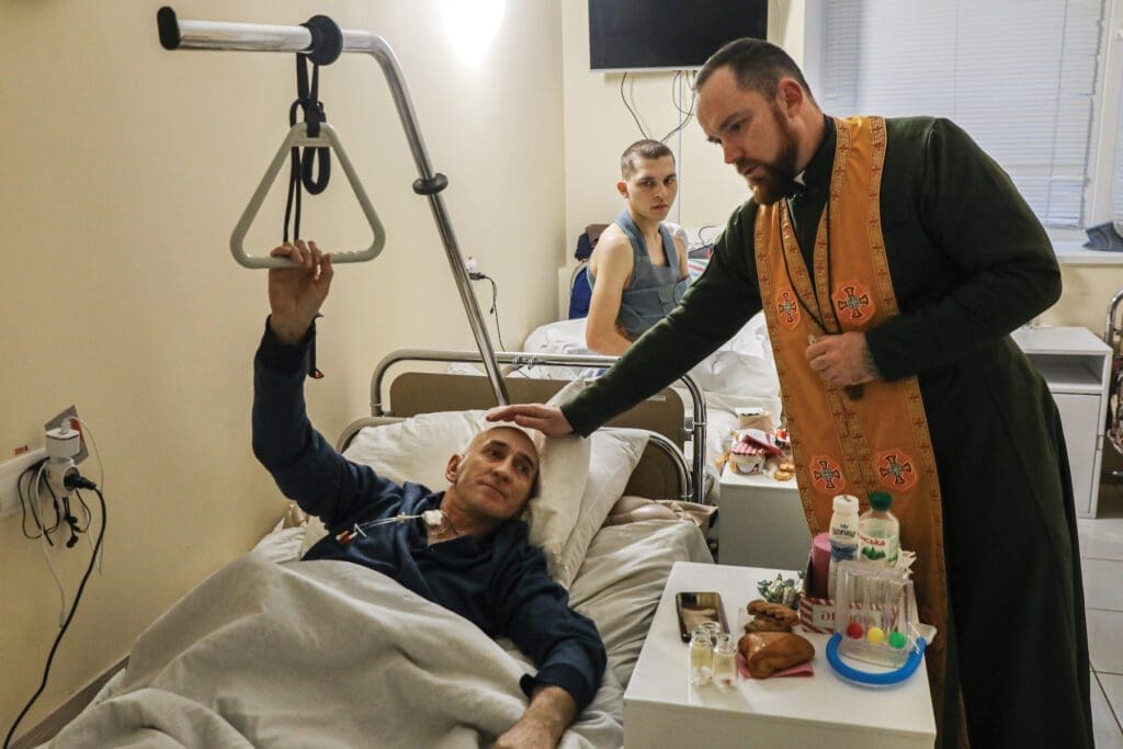 Father Yevhen Cherniuk visits with wounded soldiers at the military hospital in Kyiv.